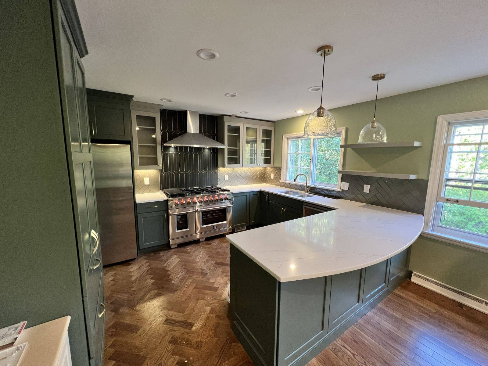 Custom green cabinetry and herringbone backsplash by Resolute Construction and Remodel